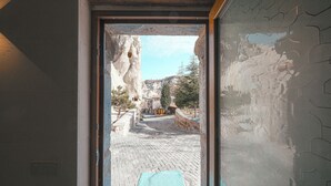 Une vue à travers une porte donnant sur une rue pavée, avec des bâtiments et une montagne en arrière-plan.