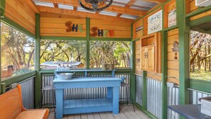 A rustic wooden structure with a blue table and benches, labeled "She Shed."
