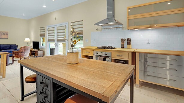 A modern kitchen with a wooden island, stainless steel appliances, and a large window. - The Main House at Starlight Meadow (Wimberley)