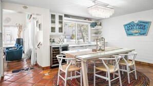 Een moderne keuken met witte kasten, een eettafel met vier stoelen en een kroonluchter.