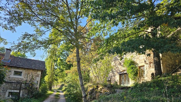 Un edificio rústico de piedra con un camino de tierra que lleva a una puerta de madera.