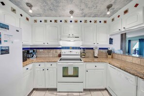 A kitchen with white cabinets, a white stove, and a blue backsplash. - Beachfront Mariner West 203 FREE Golf&Perks! Gulf Front Pool, Tennis & Grill! (Panama City Beach)