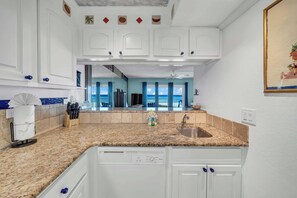 A kitchen with white cabinets, a granite countertop, and a dishwasher. - Beachfront Mariner West 203 FREE Golf&Perks! Gulf Front Pool, Tennis & Grill! (Panama City Beach)