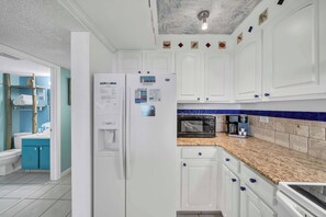 A modern kitchen with white cabinets, a microwave, and a coffee maker. - Beachfront Mariner West 203 FREE Golf&Perks! Gulf Front Pool, Tennis & Grill! (Panama City Beach)