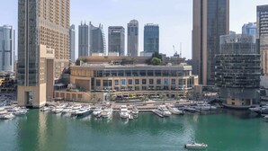 A marina with yachts docked, surrounded by high-rise buildings.