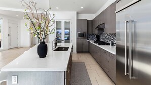 A modern kitchen with a large island, stainless steel appliances, and a decorative vase.