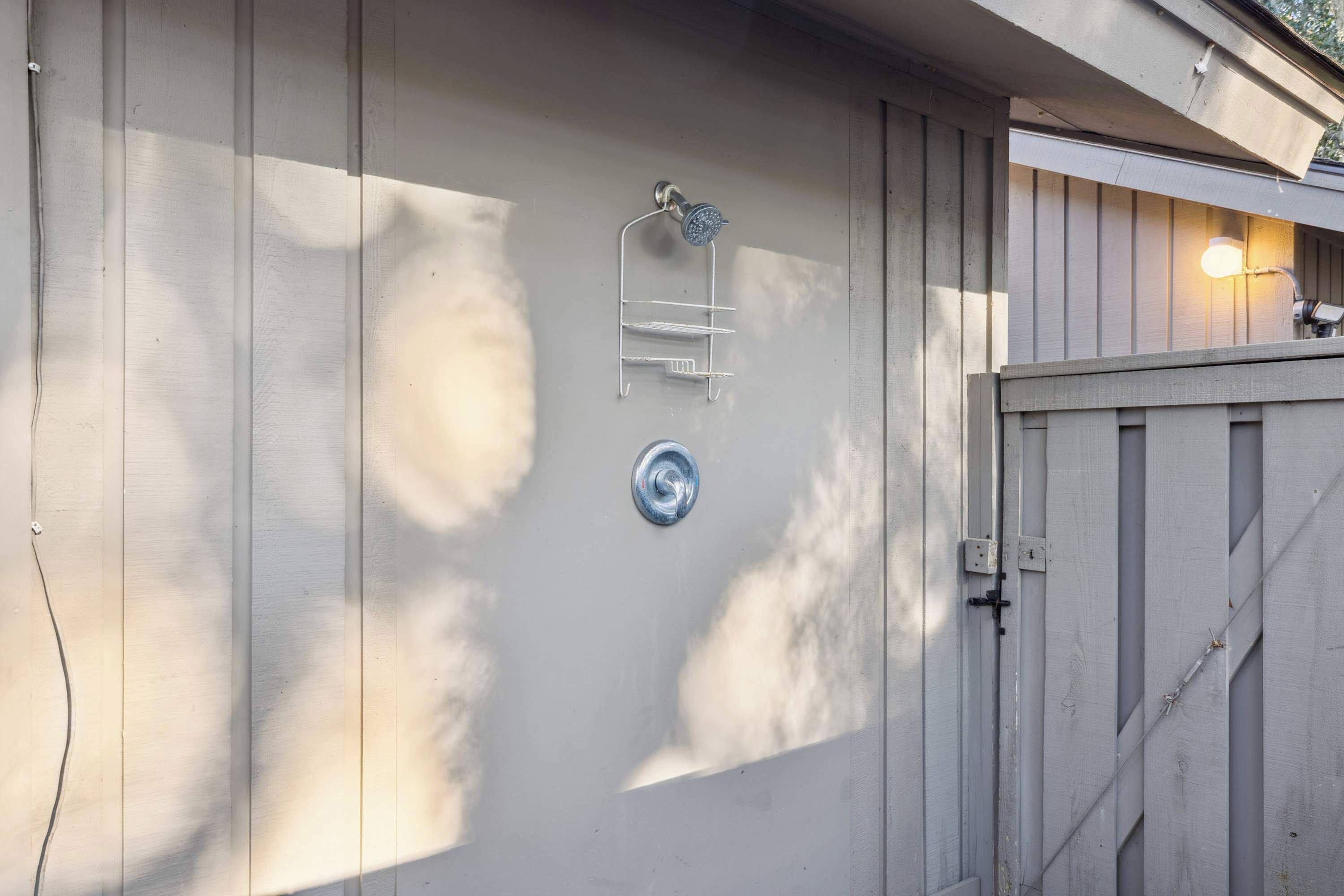 Fachada de edificio con un estante metálico, un accesorio de luz y una puerta.