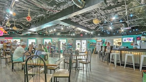 Un restaurant avec des tables et des chaises, un coin bar et un écran de télévision.