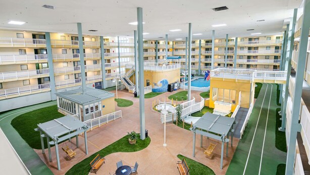 Un atrium d’hôtel à plusieurs niveaux, doté de balcons, d’une piscine et d’un espace de jeux pour enfants.