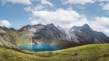 A mountainous landscape with a clear blue lake surrounded by rocky terrain and grassy areas.