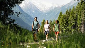Tres personas caminando por un sendero rodeado de vegetación y montañas.