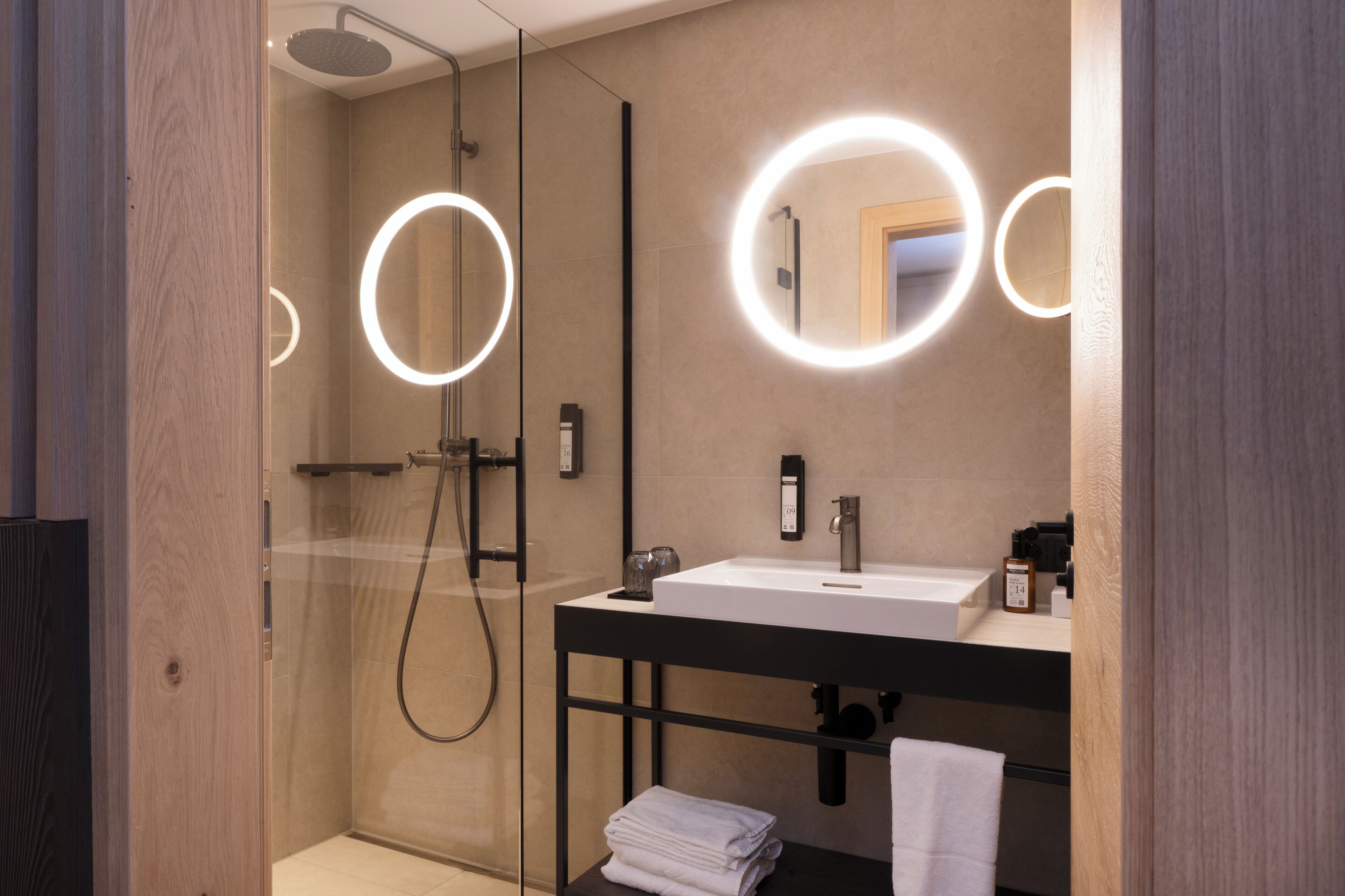 Ein modernes Badezimmer mit einer gläsernen Duschkabine, einem Waschbecken mit Spiegel und einem Handtuchhalter.