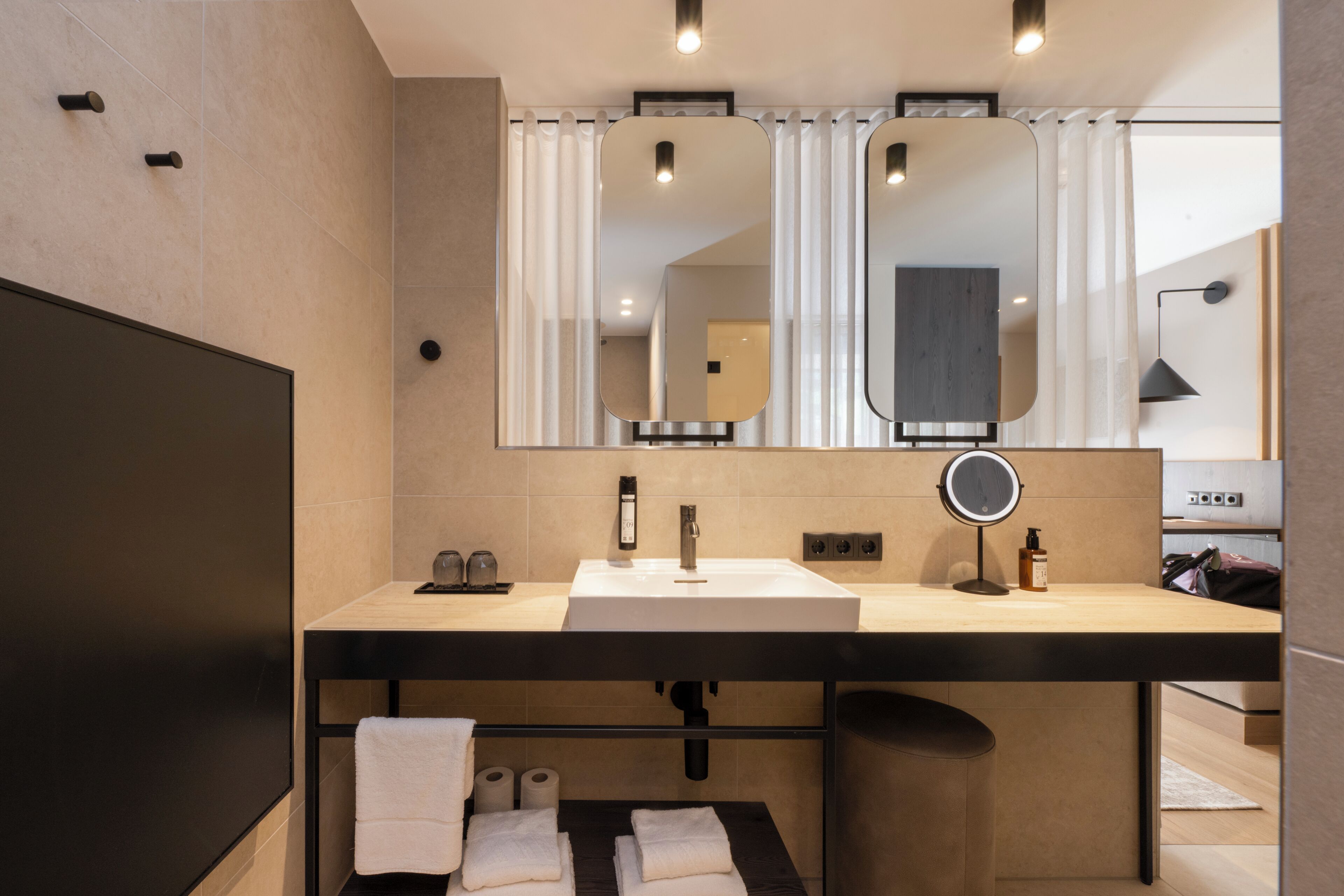 A modern bathroom with a large mirror, a sink, and a towel rack.