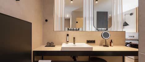 A modern bathroom with a large mirror, a sink, and a towel rack.