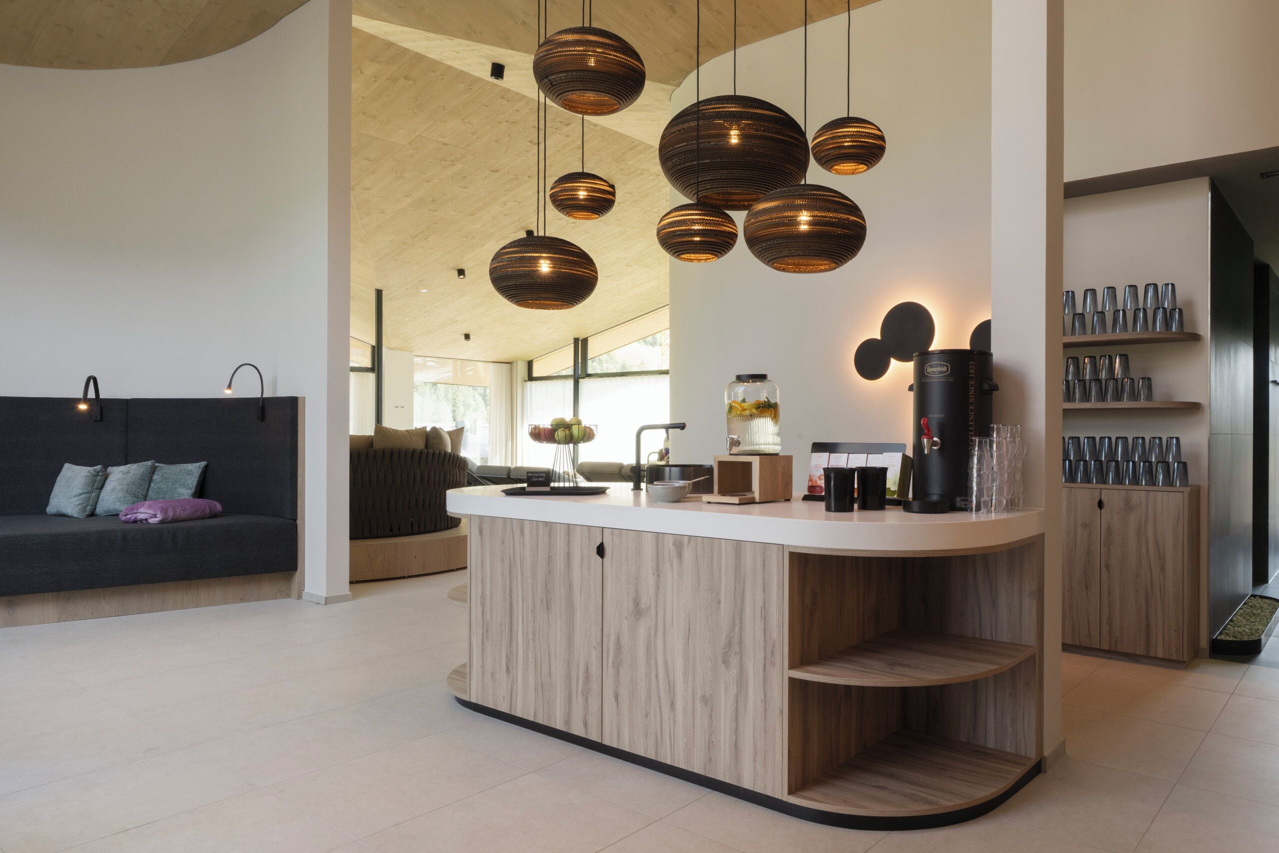 A modern kitchen with a central island, pendant lighting, and a coffee machine.
