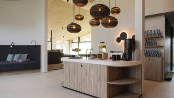 Una cucina moderna con isola centrale, illuminazione a sospensione e macchina da caffè.