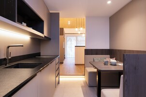A modern kitchen with a built-in oven, a sink, and a dining area with a table and chairs.