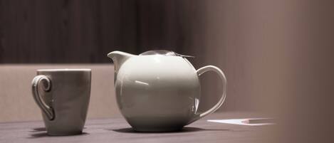 Una jarra de cerámica blanca y una taza a juego sobre una superficie de madera.