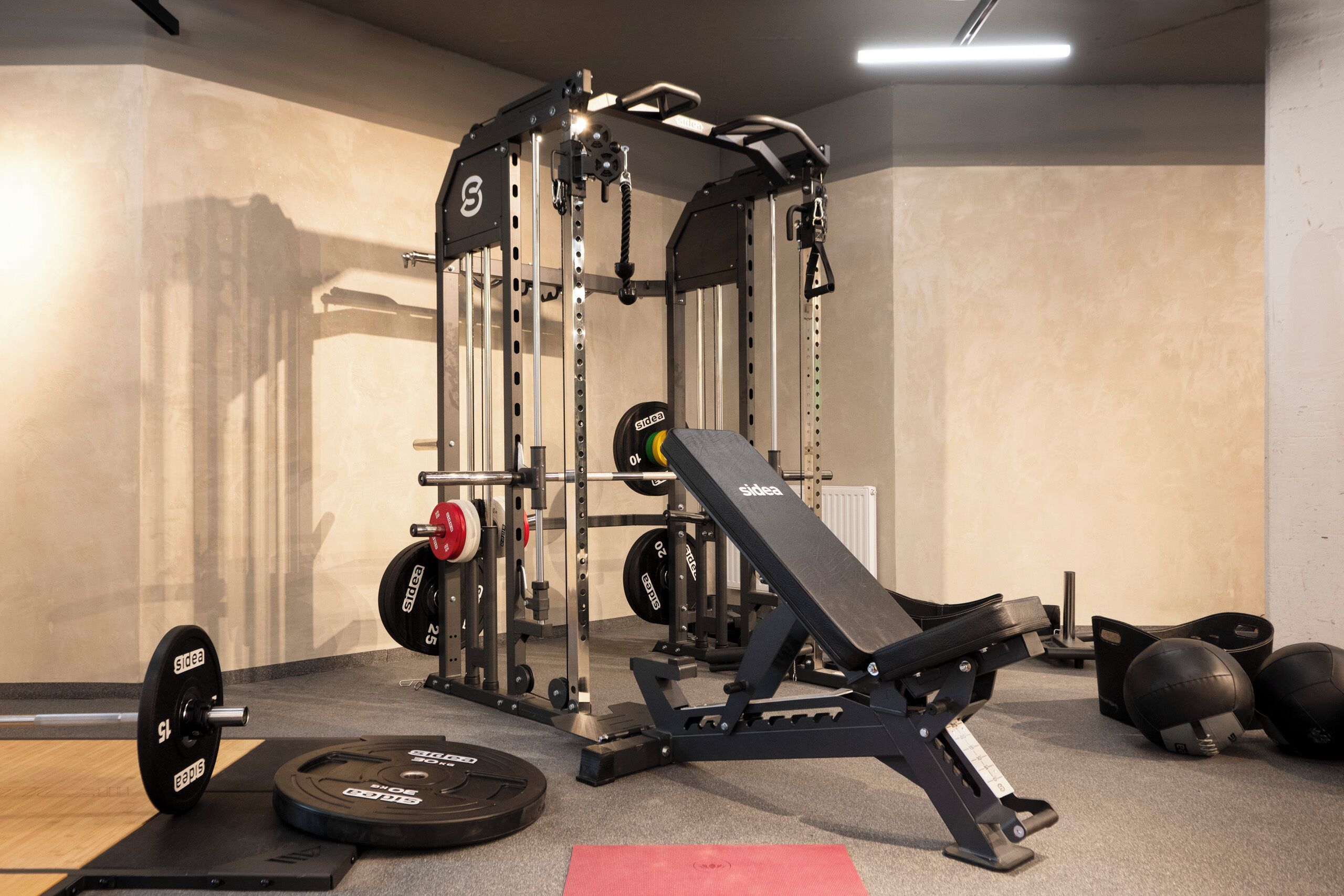A weightlifting area with a Smith machine, barbell, weight plates, and a bench.