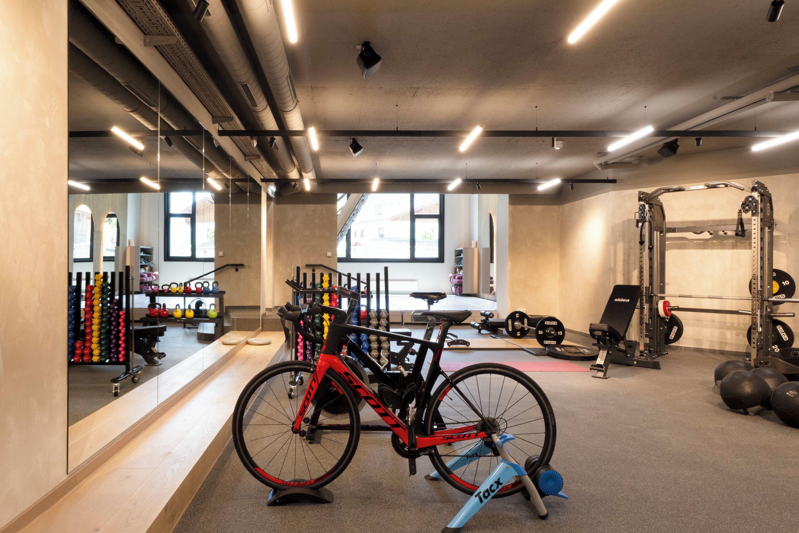 A gym with a stationary bike, weightlifting equipment, and kettlebells.