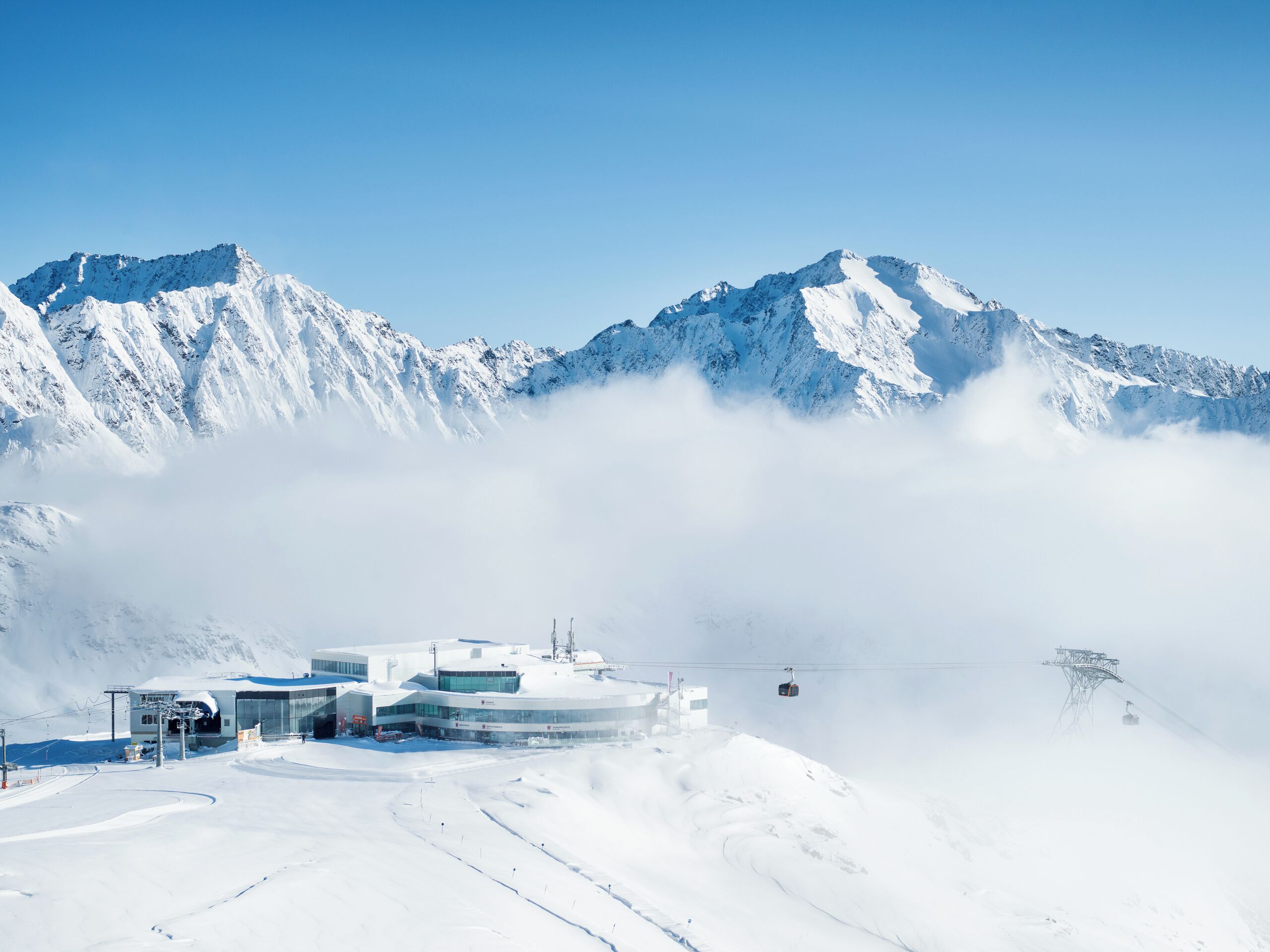 Una montagna innevata con una seggiovia e un edificio con ampie finestre.