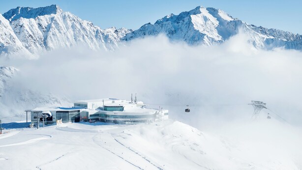Een met sneeuw bedekte berg met een skilift en een gebouw met grote ramen.