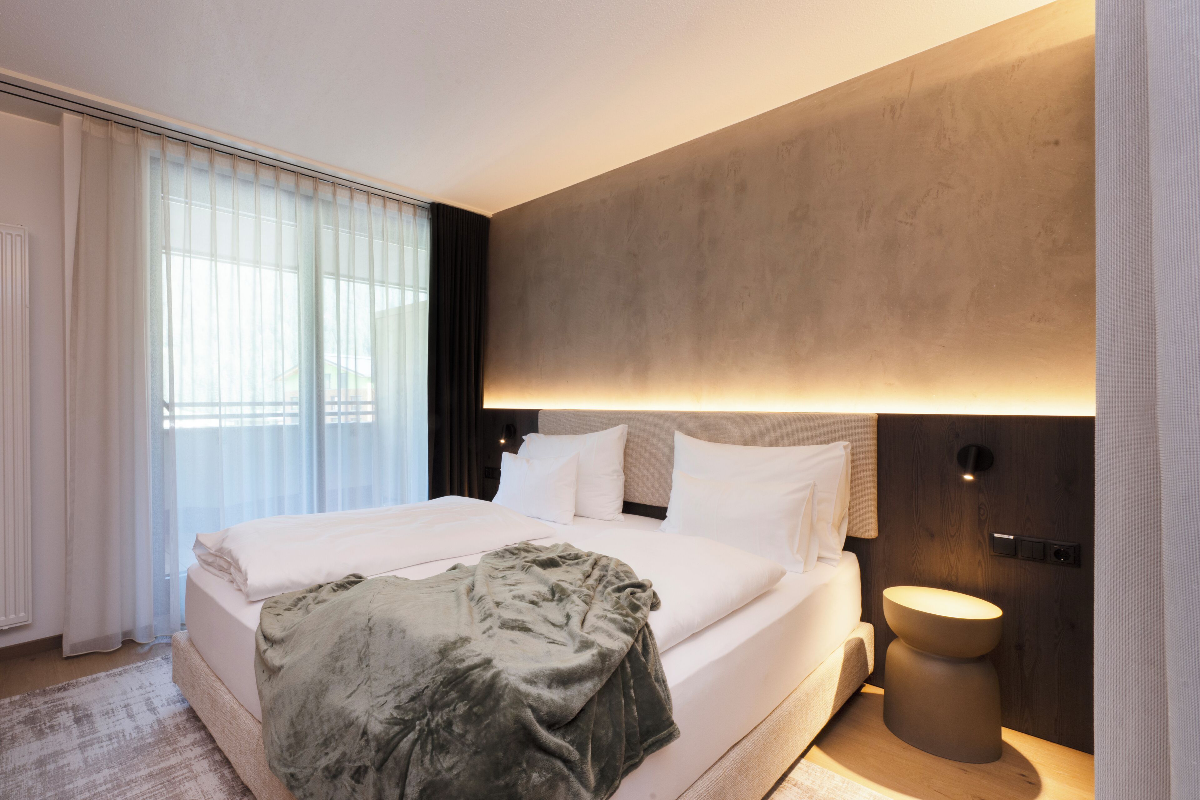 Ein modernes Hotelzimmer mit einem großen Bett, einem Nachttisch und einer Wandlampe.