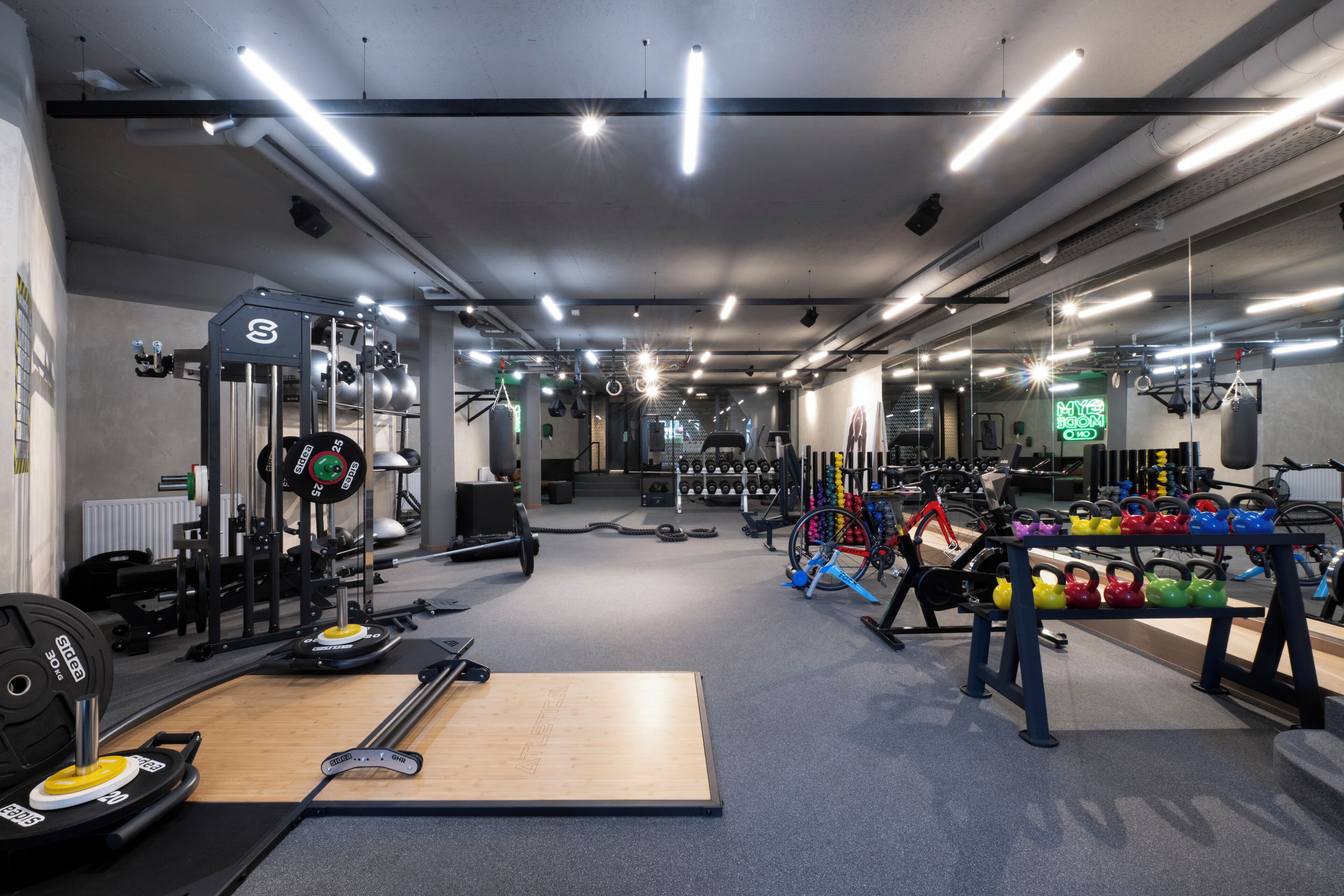 A gym with various exercise equipment, including weight machines, free weights, and kettlebells.