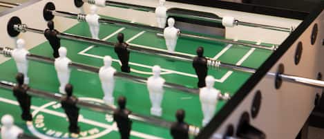 A close-up of a foosball table with two teams of figures, one in black and one in white, on a green playing surface.