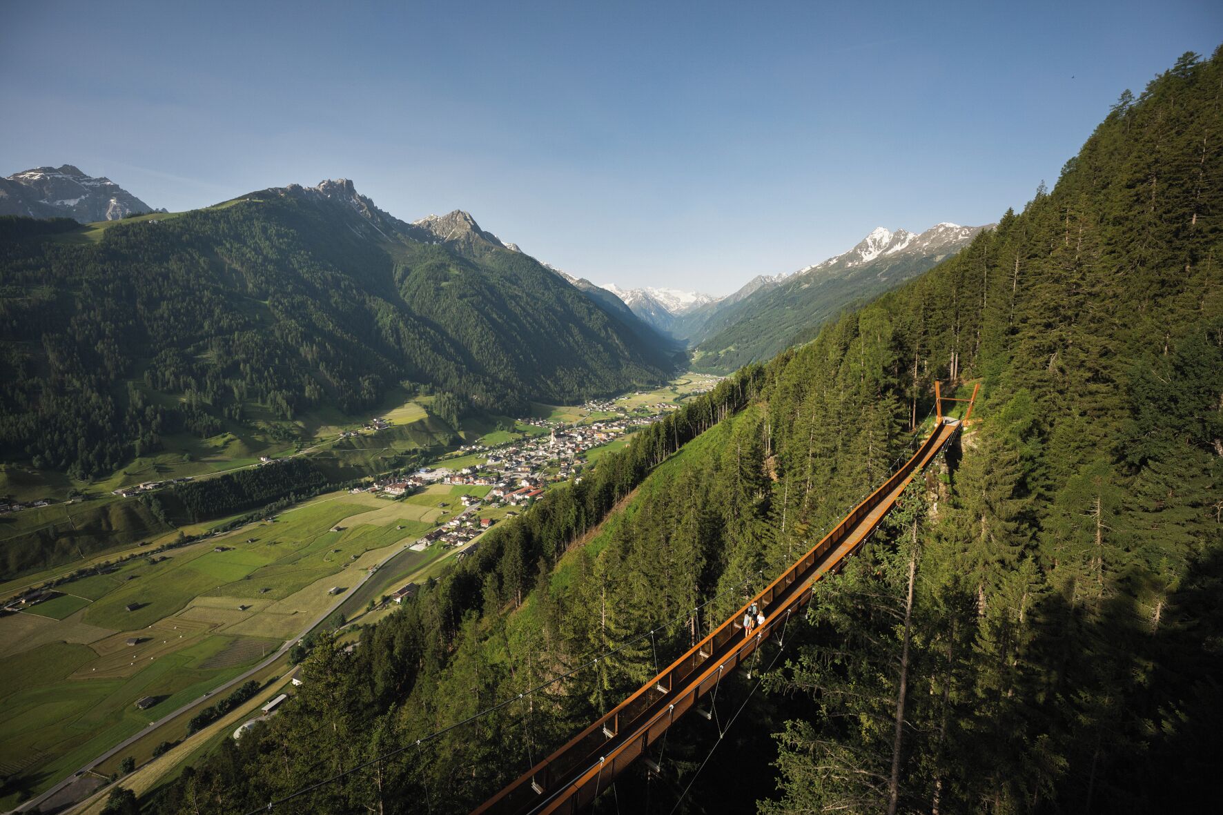 Een schilderachtig berglandschap met een houten hangbrug.