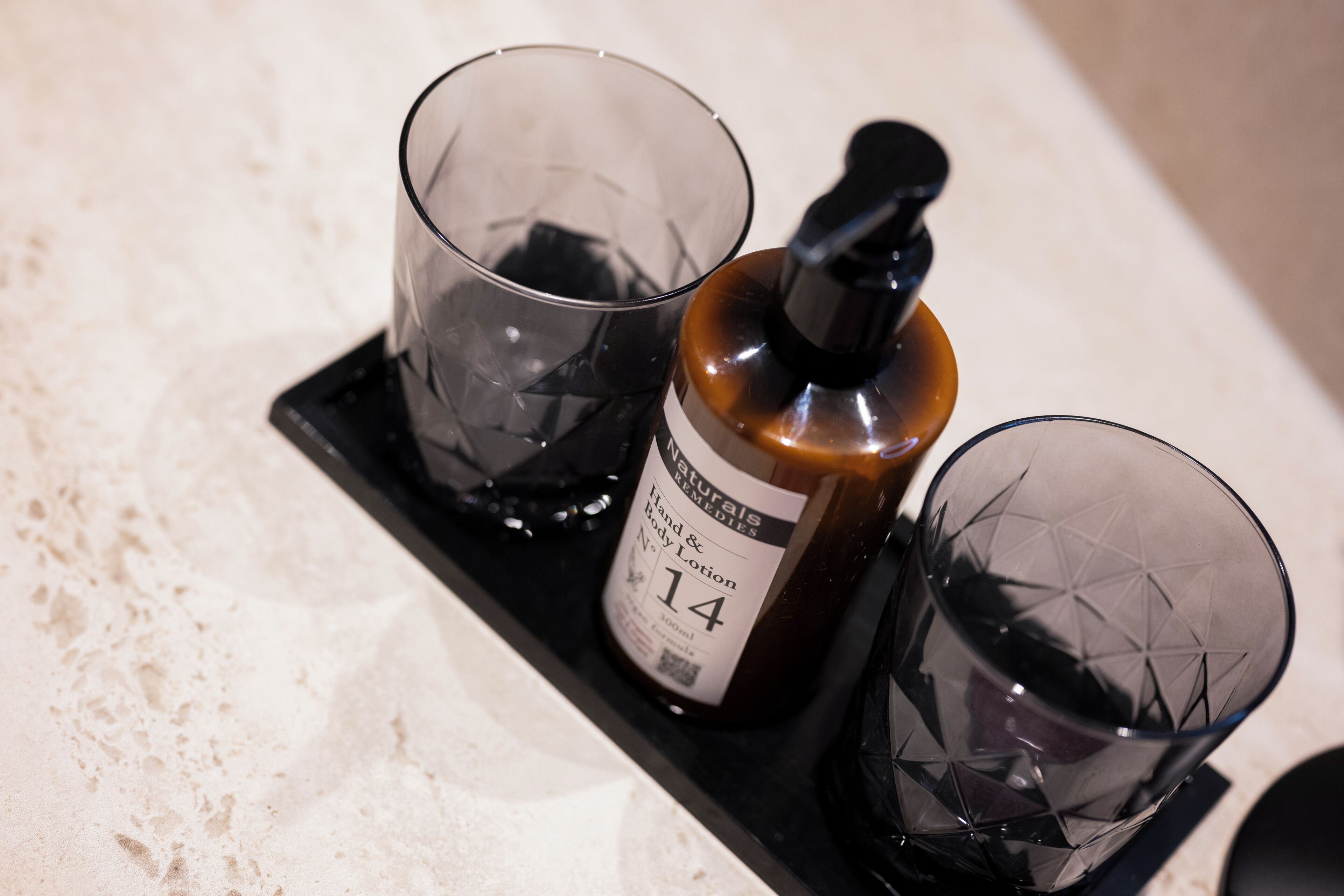 Un plateau avec trois verres et une bouteille de lotion pour les mains et le corps.