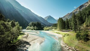 A river flowing through a mountainous landscape with dense forests and clear skies. - ELVA Premium Apartment Hotel (Neustift Im Stubaital)