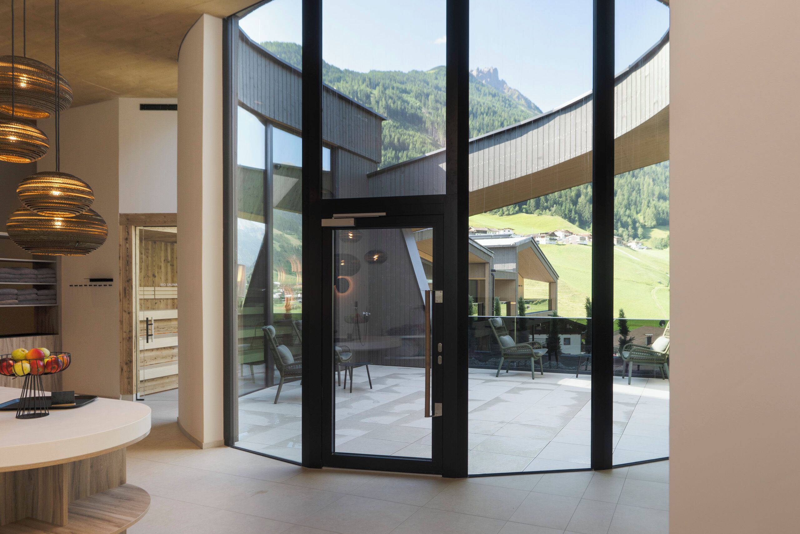 A modern interior with a large glass door leading to an outdoor patio with a scenic mountain view.