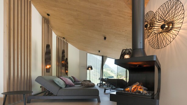 A modern living room with a sofa, a fireplace, and a view of the outdoors. - ELVA Premium Apartment Hotel (Neustift Im Stubaital)