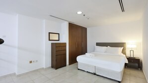 Una habitación de hotel con cama, mesita de noche, armario y espejo.