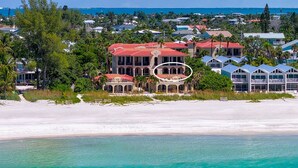 A beachfront property with a large building featuring a red roof, multiple balconies, and a view of the ocean. - La Casa AMI Beachside-Beachfront Condo w/ Heated Pool, Hot tub & Garage Parking (Holmes Beach)