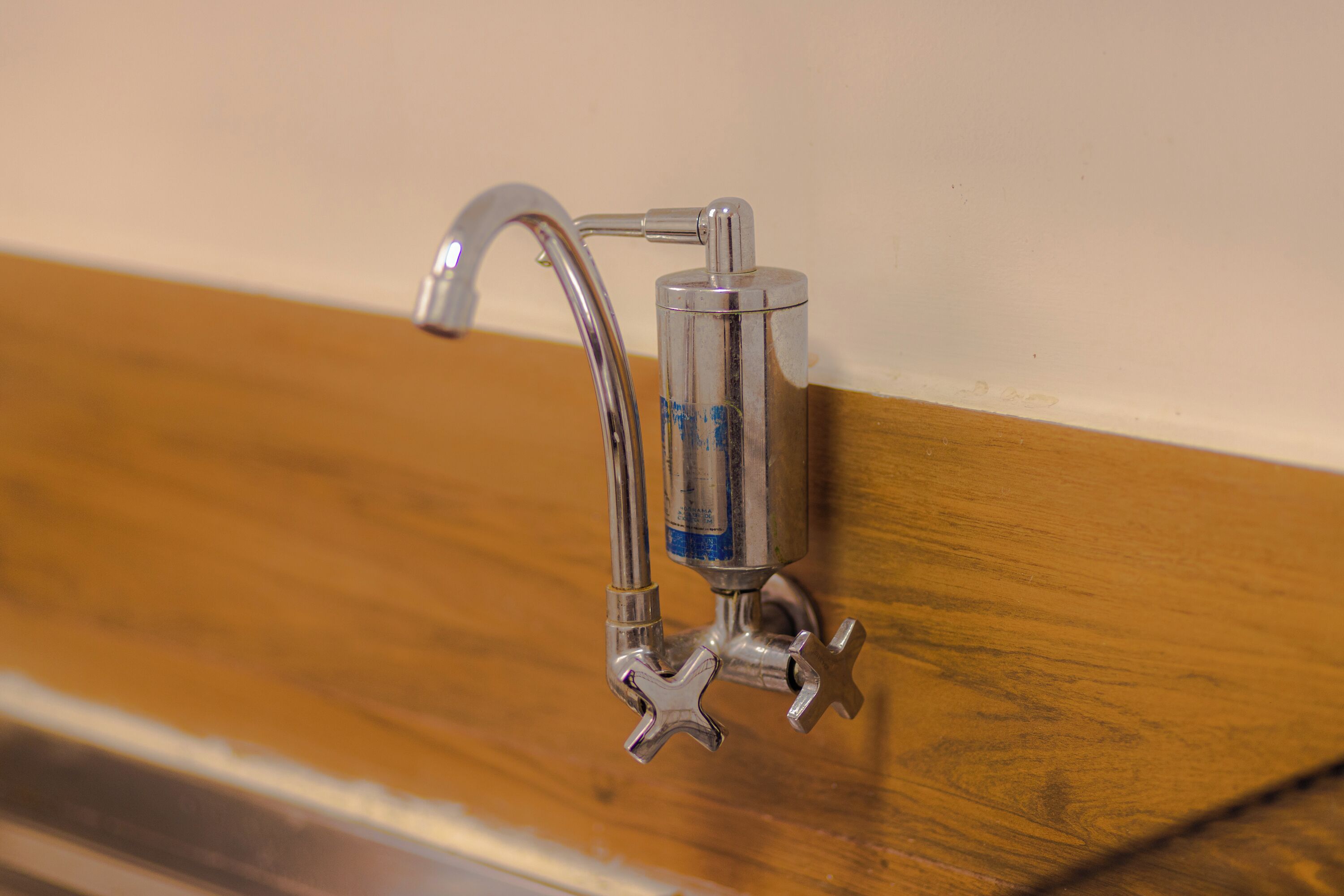 Un baño con tocador de madera y grifo cromado.