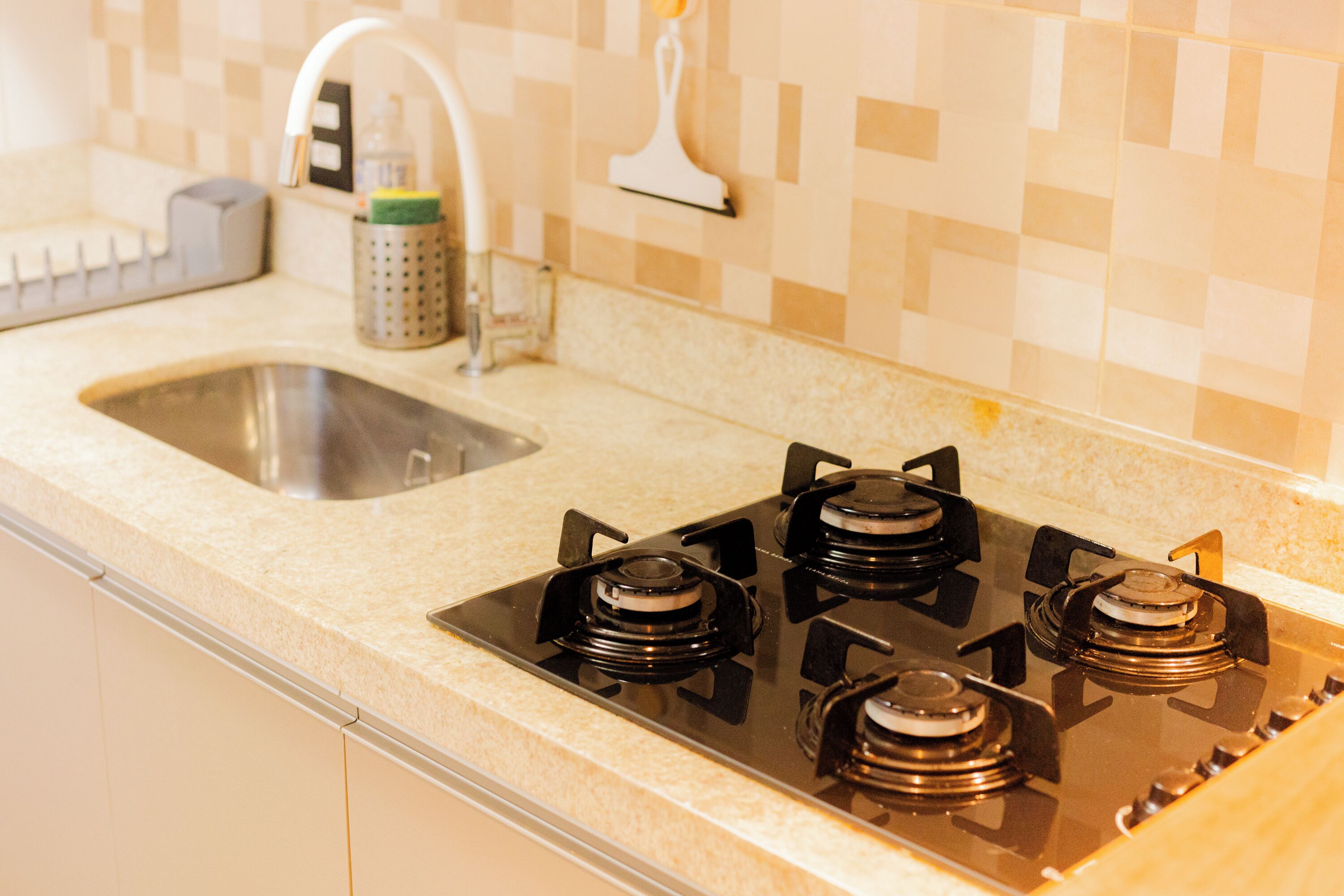 A kitchen with a gas stove, a sink, and a tiled backsplash.