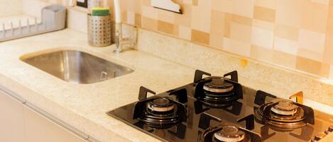 A kitchen with a gas stove, a sink, and a tiled backsplash.