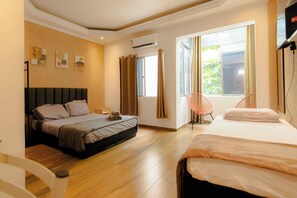 Un dormitorio con dos camas, una ventana con cortinas, una silla y obras de arte en la pared.