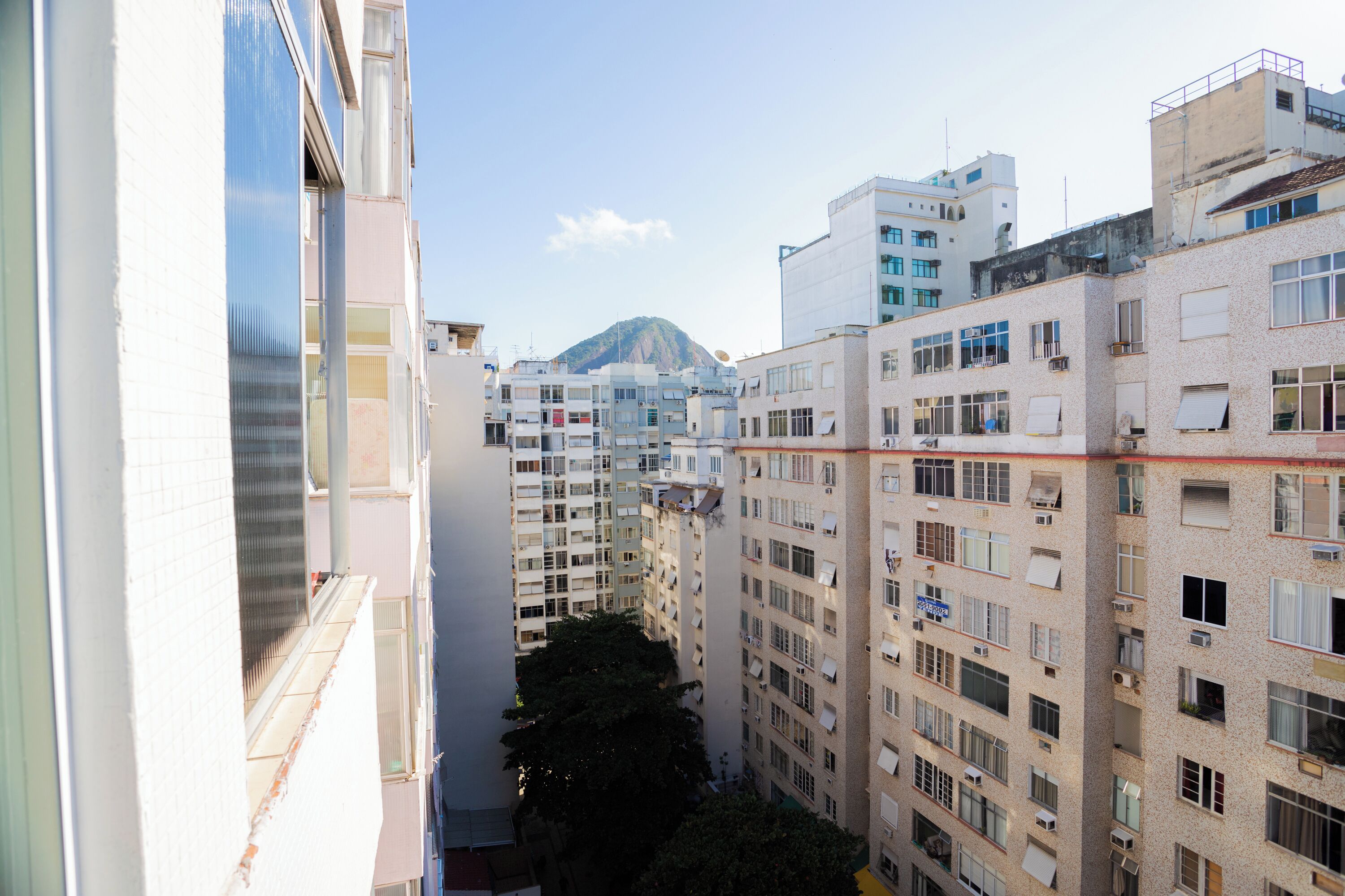 A high-rise residential building with multiple balconies and a mountain in the background.