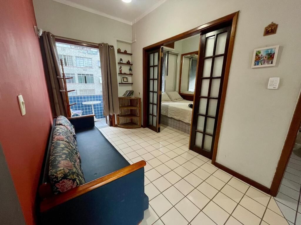 A room with a sofa, a small table, a mirror, and a view of a building outside.