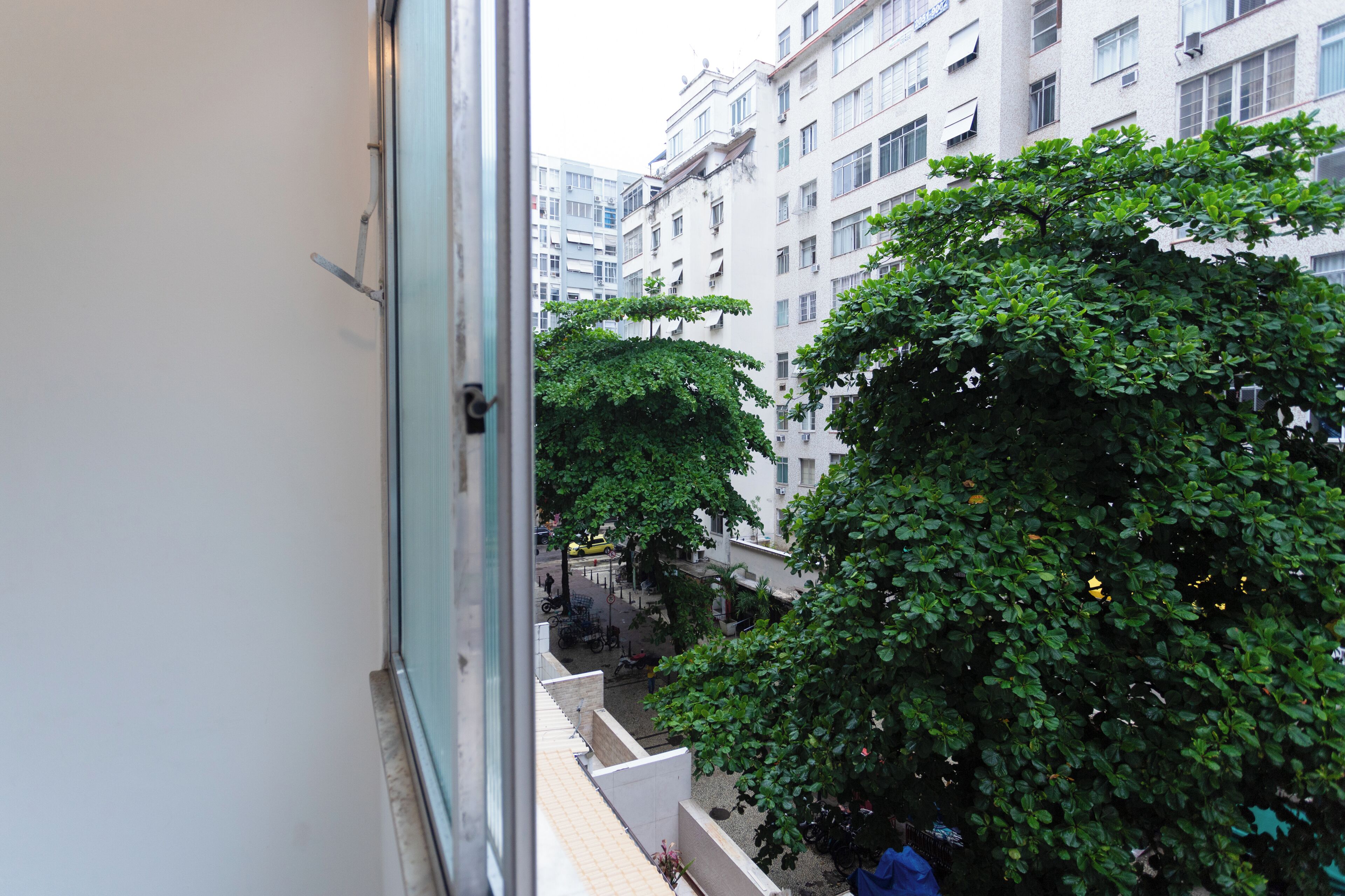 A view from a window overlooking a courtyard with trees and a building with multiple windows and balconies.
