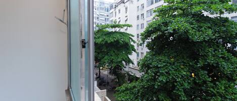 A view from a window overlooking a courtyard with trees and a building with multiple windows and balconies.