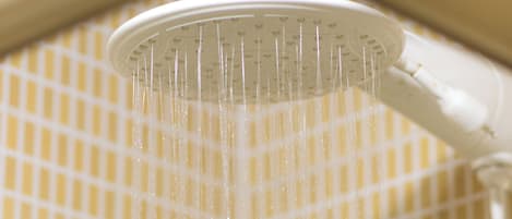 A showerhead with water flowing down a tiled wall.