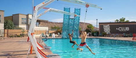 A swimming pool with a slide and climbing wall, surrounded by lounge chairs and a building labeled 'the CLUB'.