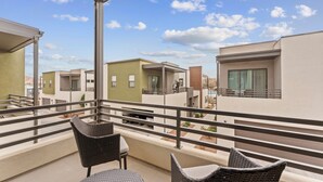 Un balcone con mobili in vimini, vista su edifici moderni e cielo sereno.