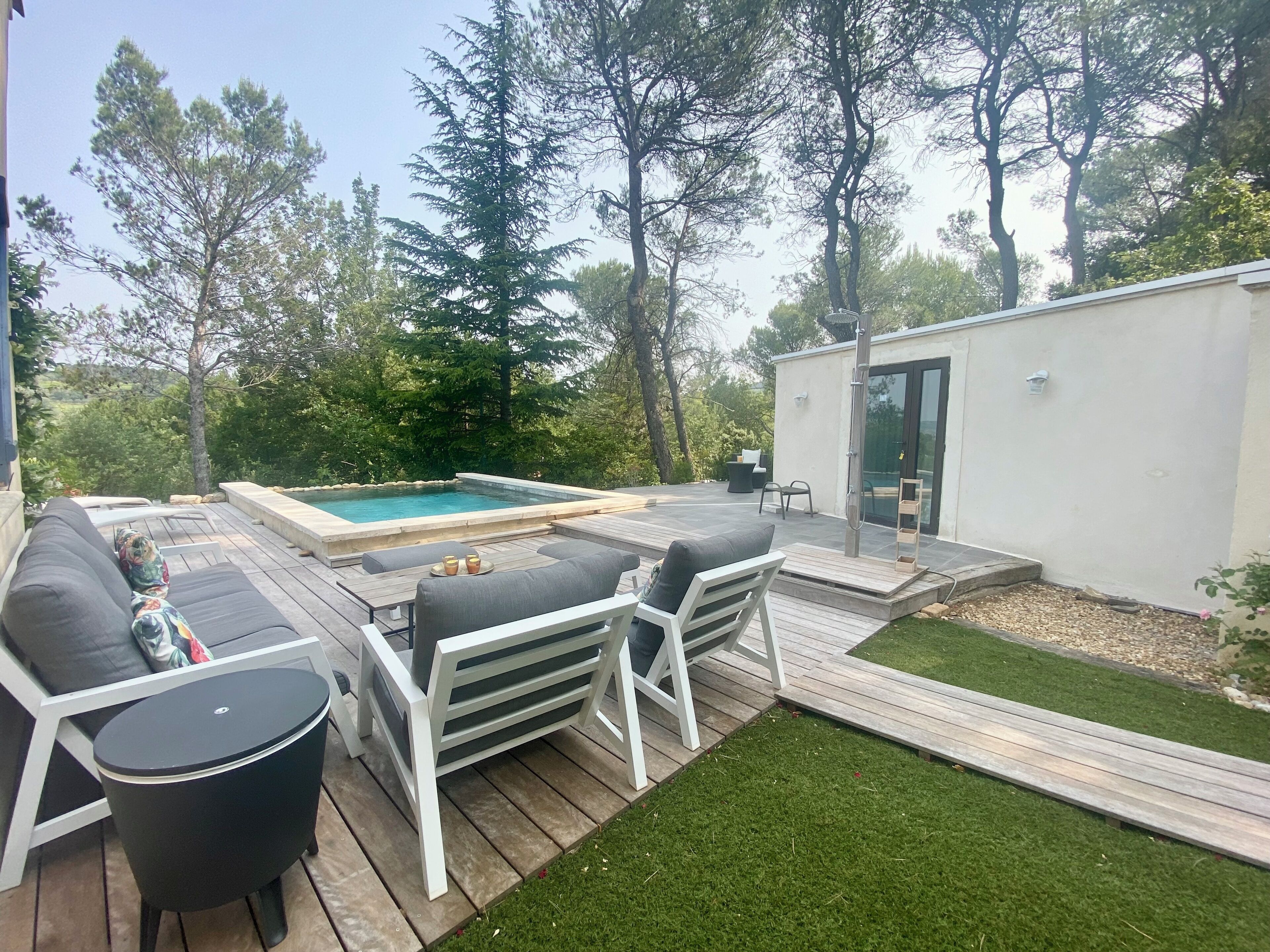 A backyard with a swimming pool, outdoor furniture, and a small building.