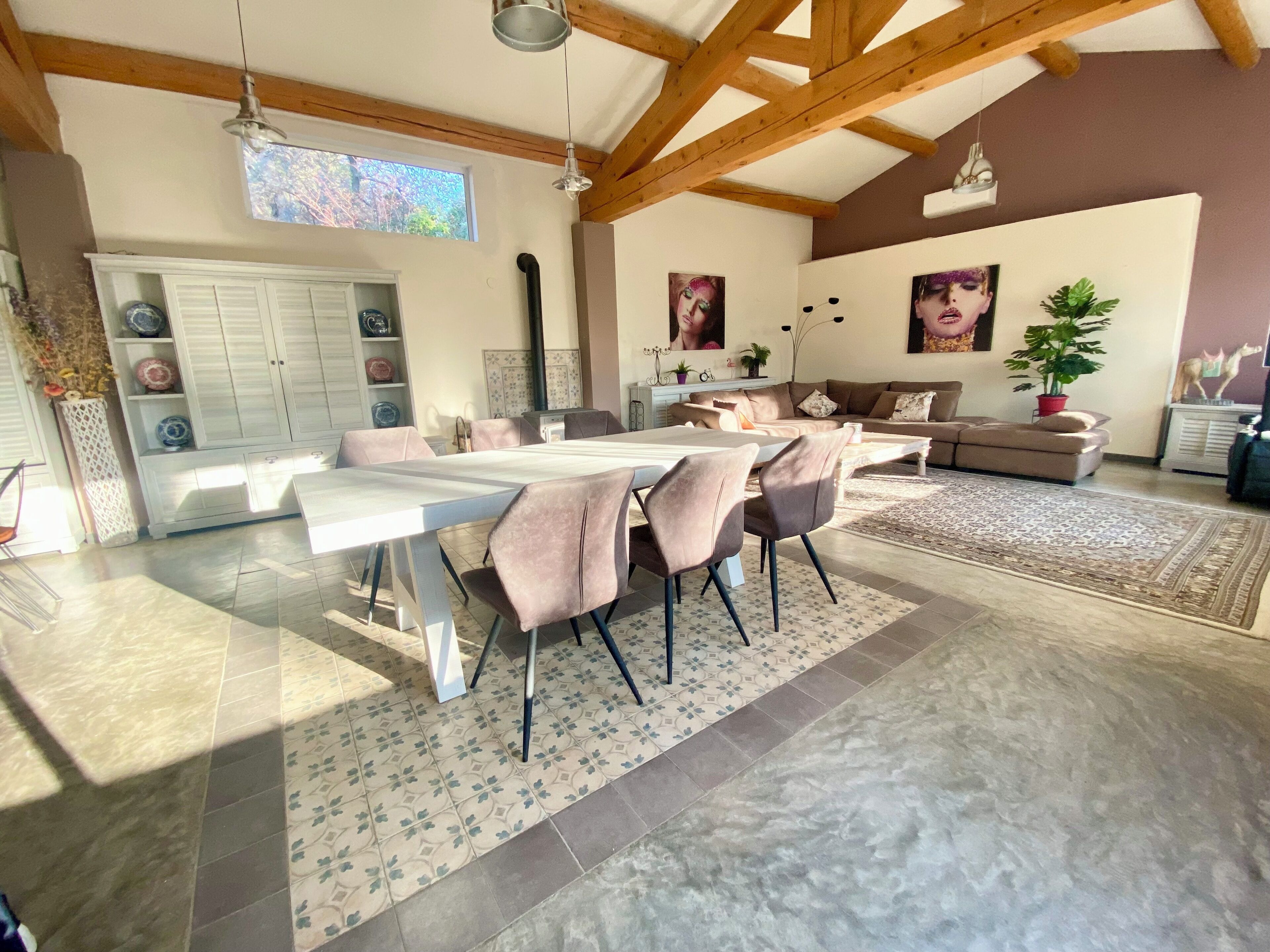 A spacious living area with a dining table, sofas, and a large window.