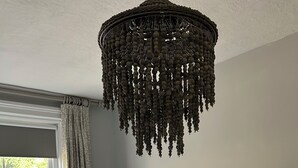 Un dormitori amb un llit gran, un llum penjant, una taula de nit amb una làmpada i una finestra amb cortines.